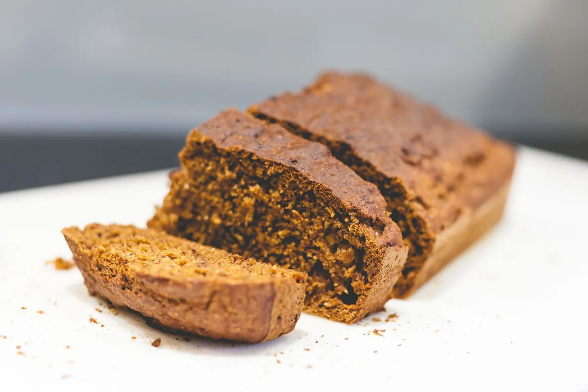 Eine dicke Scheibe saftiges Bananenbrot liegt auf einem weißen Teller.