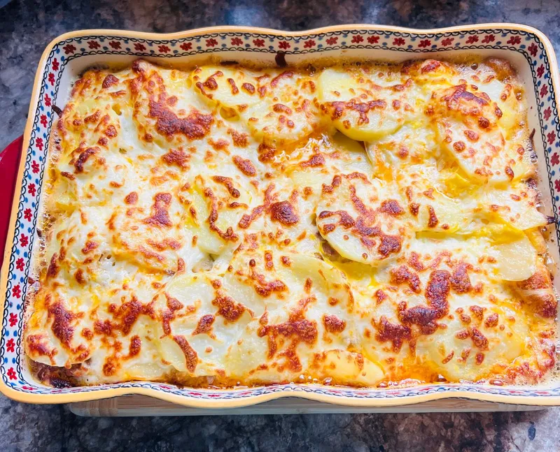 Cremiges Kartoffelgratin mit goldbrauner Käsekruste in einer Auflaufform.